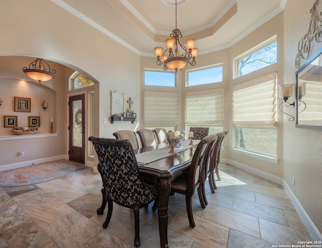 dining room featuring baseboards, arched walkways, a notable chandelier, ornamental molding, and a tray ceiling