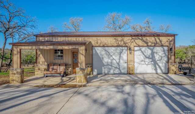detached garage with a porch and concrete driveway