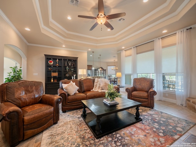 living area with crown molding, visible vents, ceiling fan, and a raised ceiling