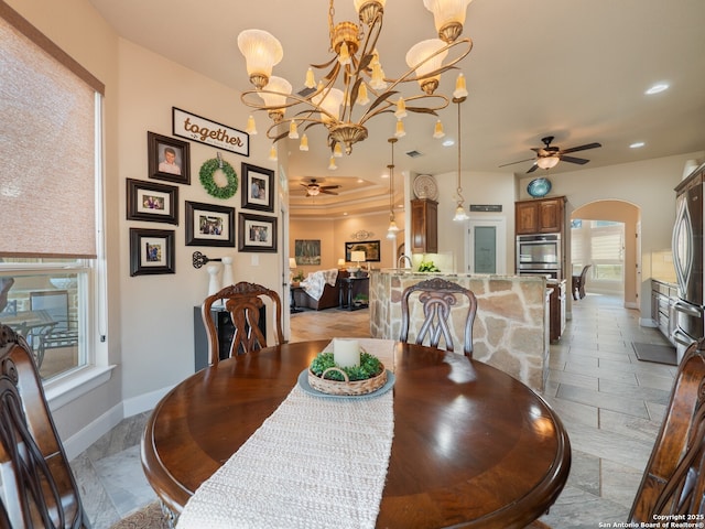 dining room featuring arched walkways, ceiling fan with notable chandelier, baseboards, and recessed lighting