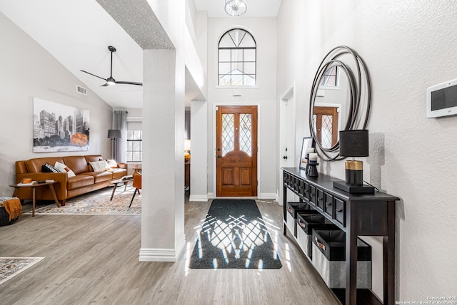 foyer with wood-type flooring, high vaulted ceiling, and ceiling fan