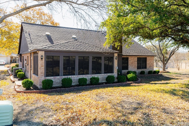 back of property with cooling unit, a sunroom, and a lawn