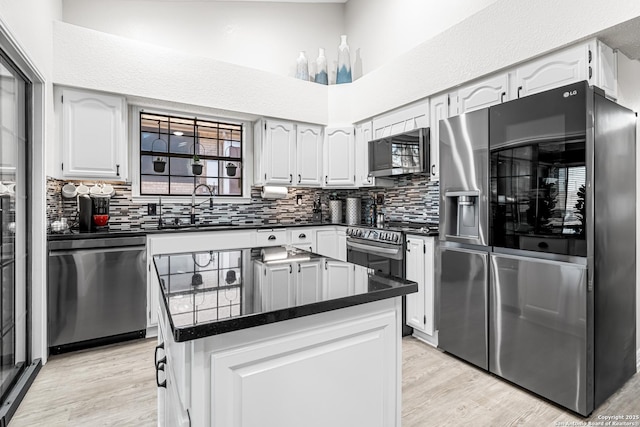 kitchen featuring white cabinetry, decorative backsplash, stainless steel appliances, and a kitchen island