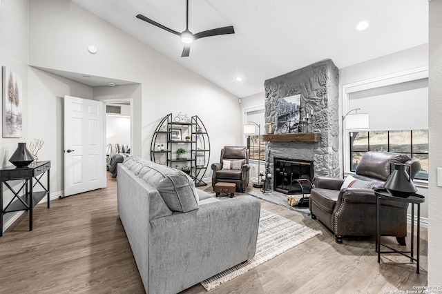 living room featuring ceiling fan, high vaulted ceiling, a stone fireplace, and hardwood / wood-style floors