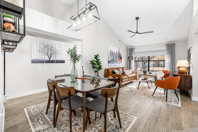 dining room with hardwood / wood-style flooring, ceiling fan, and high vaulted ceiling