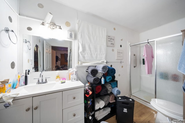 bathroom with vanity, hardwood / wood-style flooring, a shower with shower door, and toilet