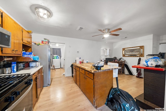 kitchen featuring independent washer and dryer, appliances with stainless steel finishes, ceiling fan, and light wood-type flooring