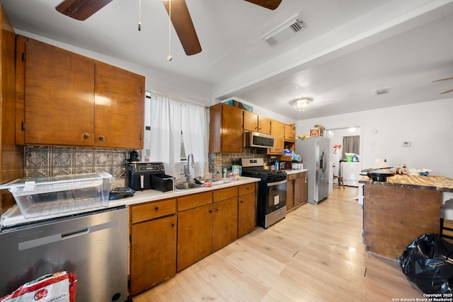 kitchen featuring sink, ceiling fan, stainless steel appliances, decorative backsplash, and light wood-type flooring