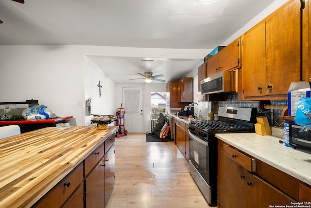 kitchen featuring tasteful backsplash, stainless steel appliances, light hardwood / wood-style floors, and ceiling fan