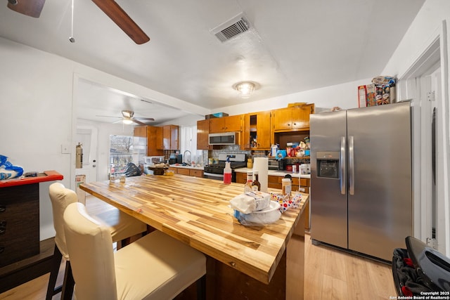 kitchen featuring sink, decorative backsplash, ceiling fan, light hardwood / wood-style floors, and stainless steel appliances