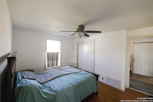 bedroom featuring dark wood-type flooring, a closet, and ceiling fan