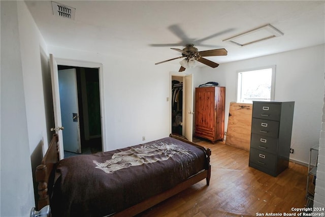 bedroom with a walk in closet, dark wood-type flooring, a closet, and ceiling fan