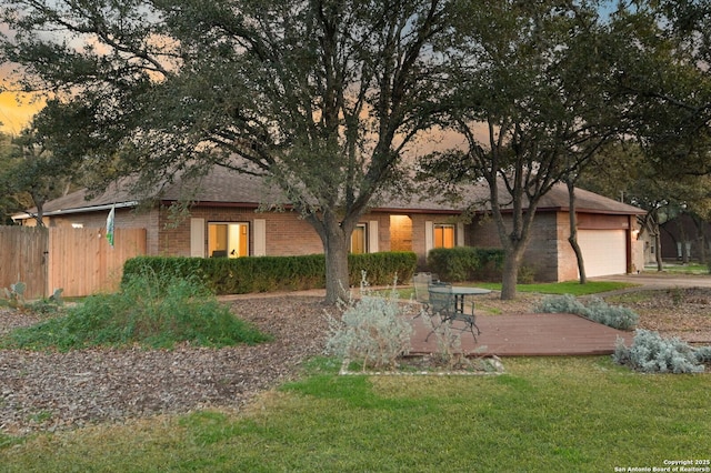 view of front of home with a front yard, brick siding, fence, and an attached garage