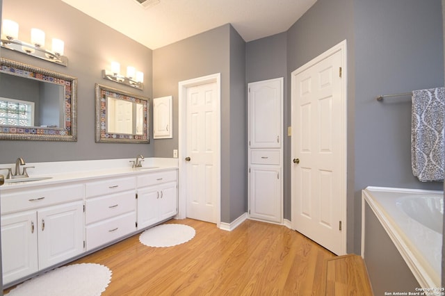 bathroom featuring double vanity, visible vents, a sink, and wood finished floors