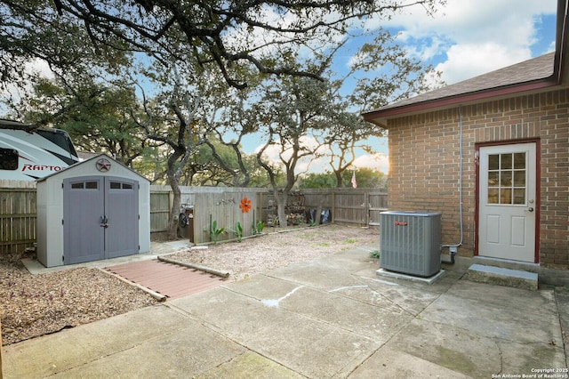 view of patio / terrace featuring a shed, a fenced backyard, cooling unit, and an outdoor structure