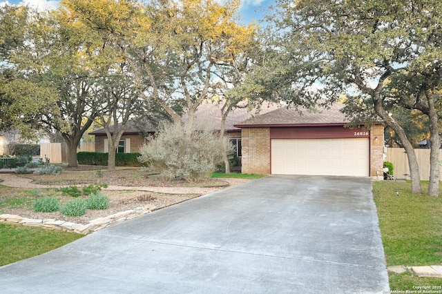 view of front of property featuring concrete driveway, brick siding, a shingled roof, and fence