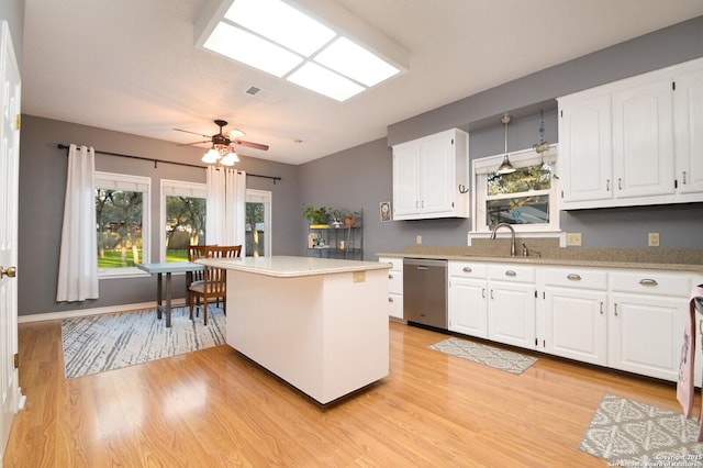 kitchen featuring light countertops, visible vents, stainless steel dishwasher, white cabinetry, and a sink