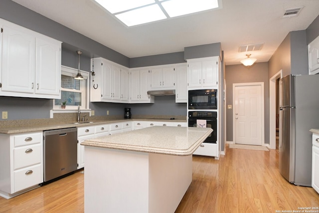 kitchen featuring black appliances, a kitchen island, light countertops, and white cabinets