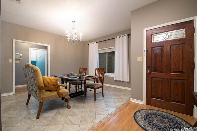 dining space with light tile patterned flooring, visible vents, baseboards, and an inviting chandelier