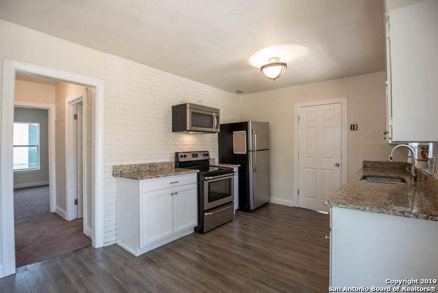 kitchen featuring appliances with stainless steel finishes, white cabinetry, sink, light stone countertops, and dark wood-type flooring