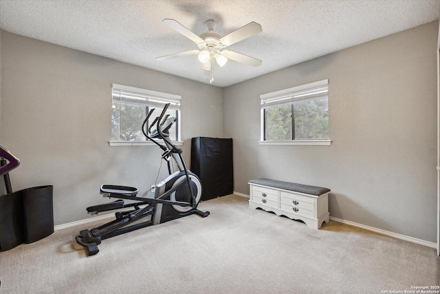 workout area with ceiling fan, light colored carpet, and a textured ceiling