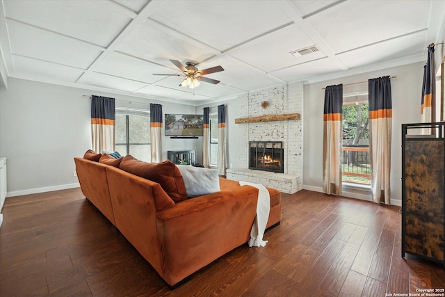 living room featuring dark wood-type flooring, coffered ceiling, and a brick fireplace