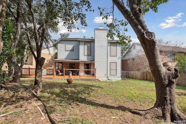 back of house featuring a wooden deck and a lawn