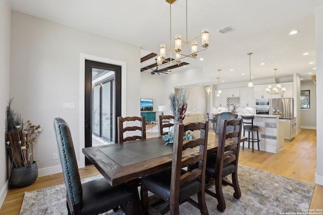 dining area with ceiling fan with notable chandelier and light hardwood / wood-style flooring