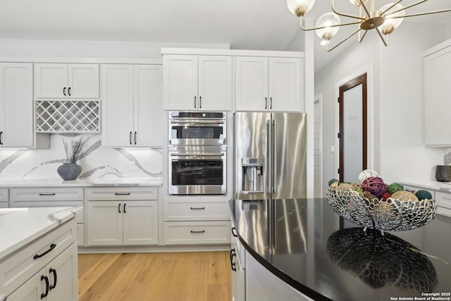 kitchen featuring white cabinetry, stainless steel appliances, light hardwood / wood-style floors, and decorative backsplash