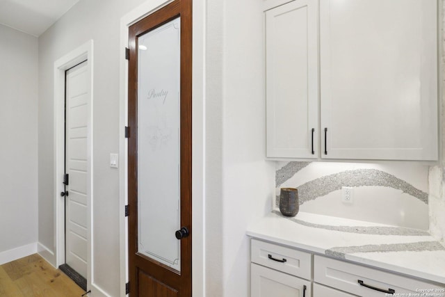 interior space featuring white cabinetry, light stone counters, and light wood-type flooring