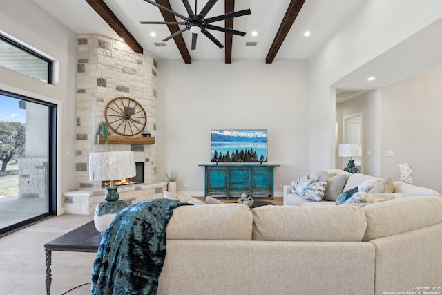 living room with a towering ceiling, a fireplace, beam ceiling, and light hardwood / wood-style flooring