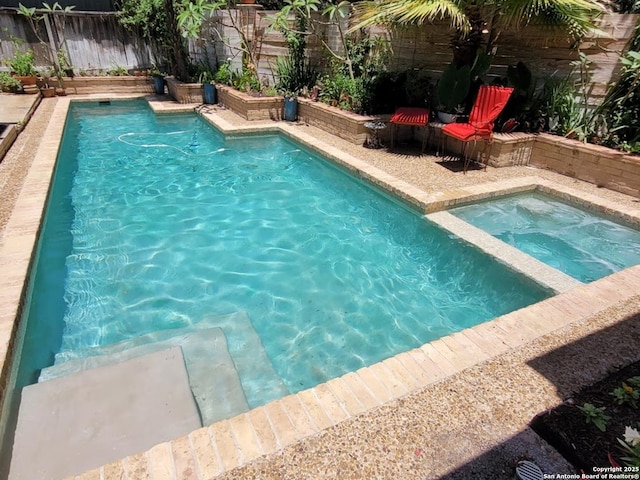 view of swimming pool featuring an in ground hot tub