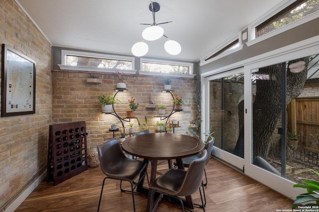 dining room featuring wood-type flooring and brick wall