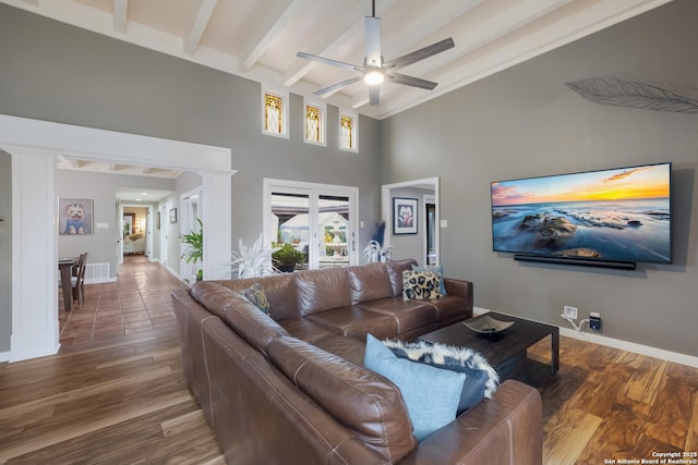 living room with ceiling fan, wood-type flooring, beam ceiling, and a towering ceiling