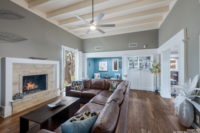 living room featuring ceiling fan, dark hardwood / wood-style flooring, lofted ceiling with beams, and ornate columns