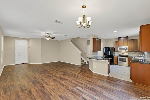 kitchen featuring appliances with stainless steel finishes, decorative light fixtures, sink, backsplash, and light hardwood / wood-style flooring