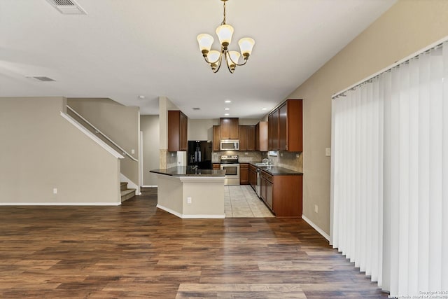 kitchen with sink, appliances with stainless steel finishes, an inviting chandelier, decorative backsplash, and decorative light fixtures