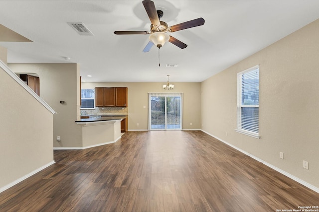 unfurnished living room featuring dark wood-type flooring and ceiling fan with notable chandelier