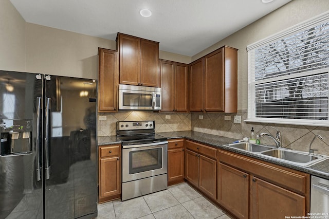 kitchen with tasteful backsplash, appliances with stainless steel finishes, sink, and light tile patterned floors