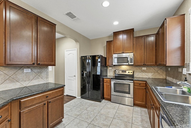 kitchen featuring sink, light tile patterned floors, backsplash, and appliances with stainless steel finishes