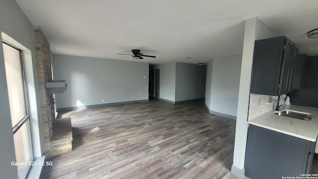 unfurnished living room with sink, dark wood-type flooring, and ceiling fan