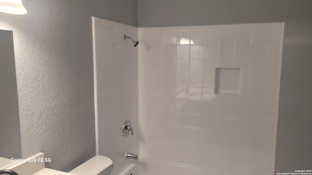 bathroom with tiled shower / bath combo and toilet