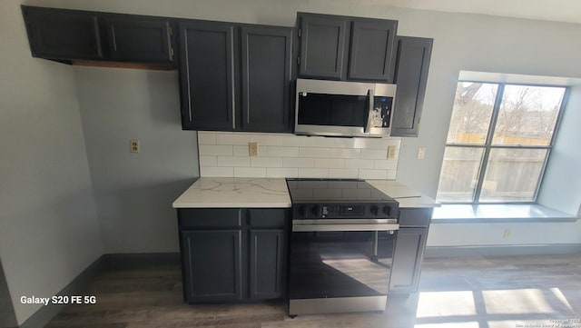 kitchen with range with electric cooktop, light stone countertops, and tasteful backsplash