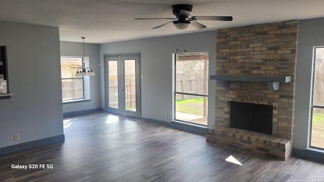 unfurnished living room with hardwood / wood-style flooring, ceiling fan, a brick fireplace, and a textured ceiling