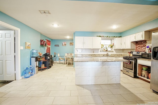 kitchen with white cabinetry, sink, light tile patterned floors, light stone counters, and stainless steel gas range