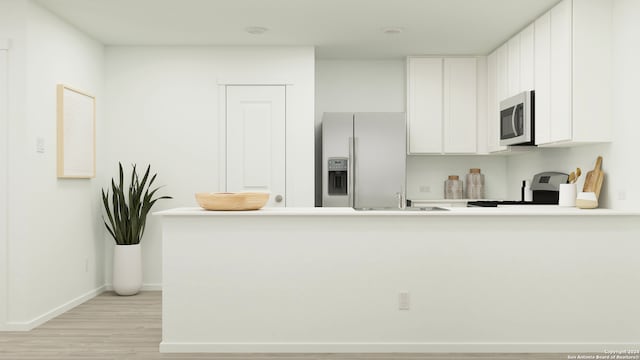 kitchen with appliances with stainless steel finishes, sink, white cabinets, kitchen peninsula, and light hardwood / wood-style flooring