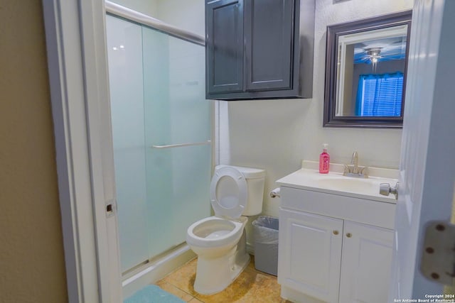 bathroom with a shower with door, vanity, tile patterned flooring, and toilet