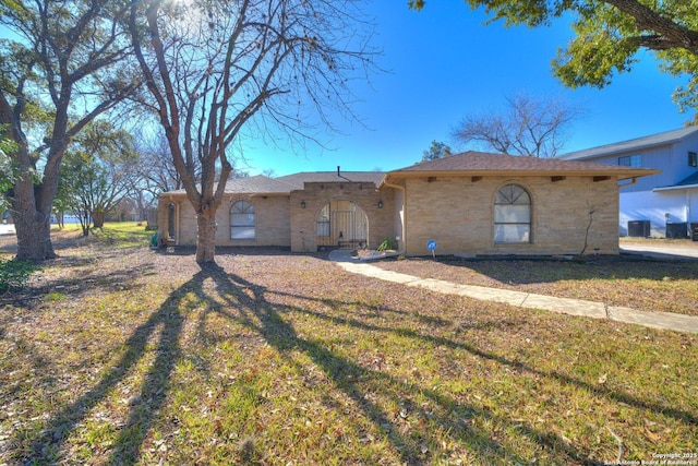 single story home with cooling unit and a front yard