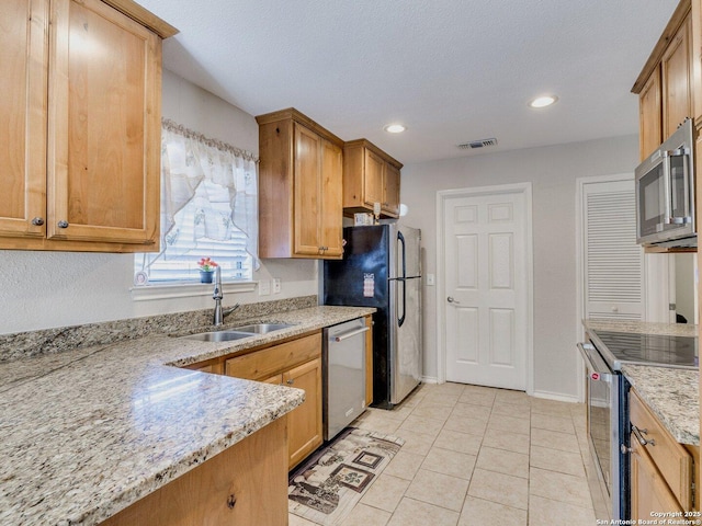 kitchen featuring light stone counters, stainless steel appliances, sink, and light tile patterned floors