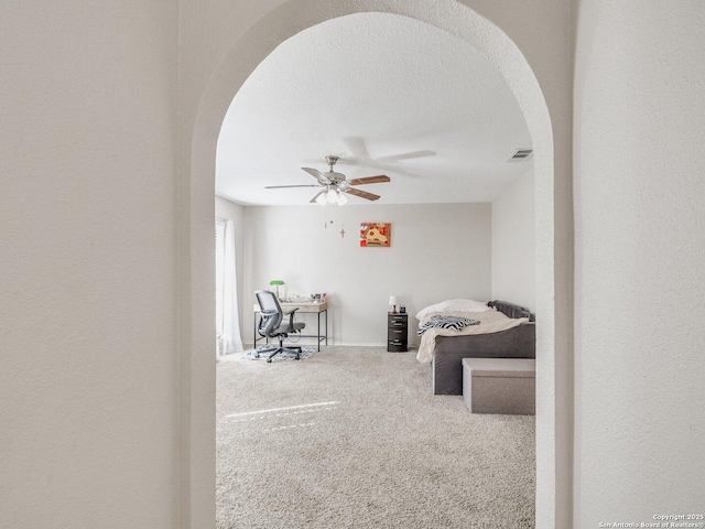 bedroom with ceiling fan, carpet flooring, and a textured ceiling